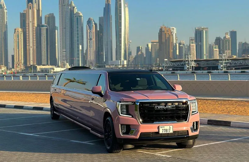 Pink GMC Yukon XL Limousine parked in Dubai, offering luxury limo rental services.